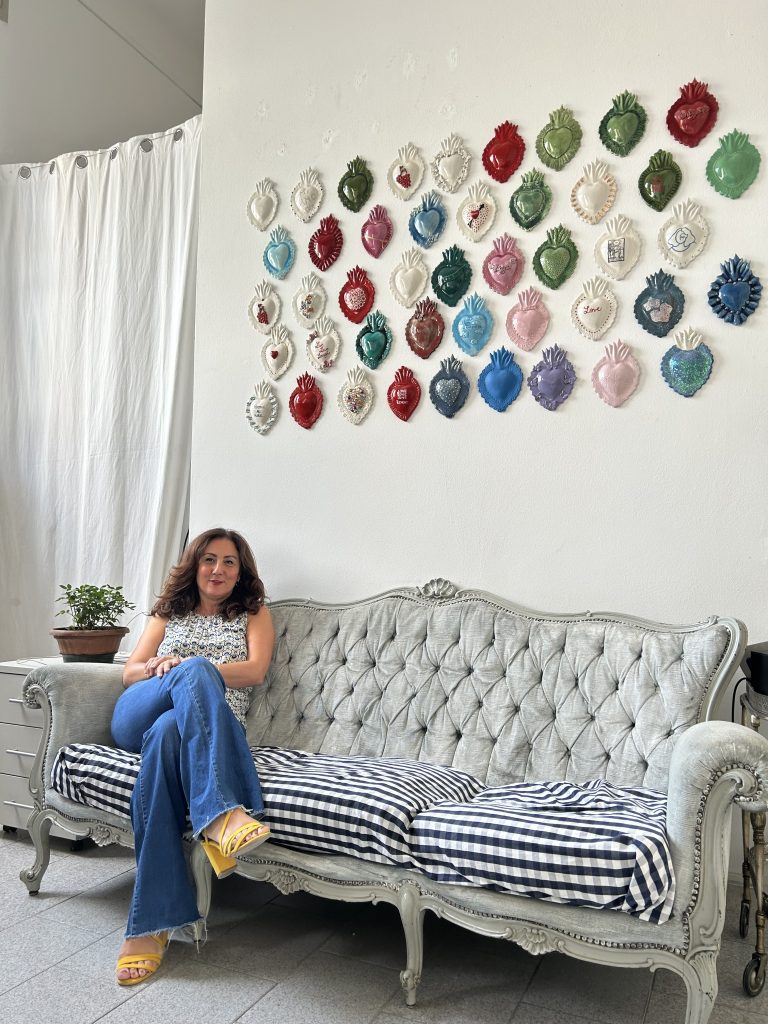 Antonella Freni nel suo atelier a Dergano con cuori sacri appesi alla parete